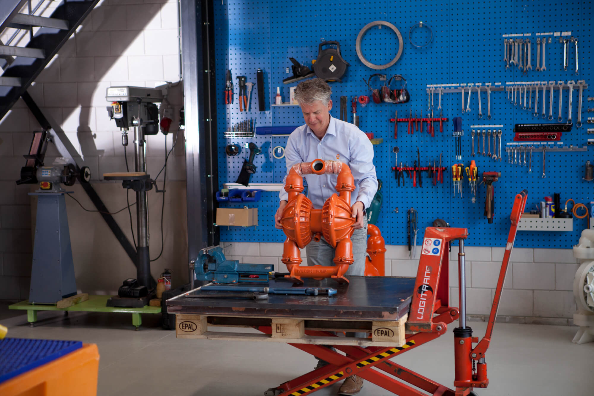 Monteur werkt een oranje Wilden-pomp af op de heftafel in onze werkplaats